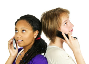 Two women demonstrating Full-Duplex communications via cell phones.
